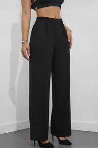 Person wearing black wide-leg pants against a white wall