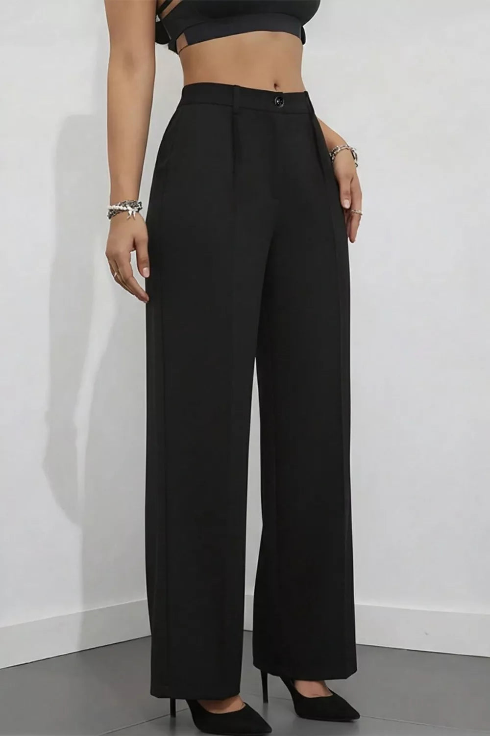 Person wearing black wide-leg pants against a white wall
