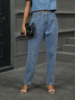 Person wearing blue jeans with pearl embellishments in an urban setting.