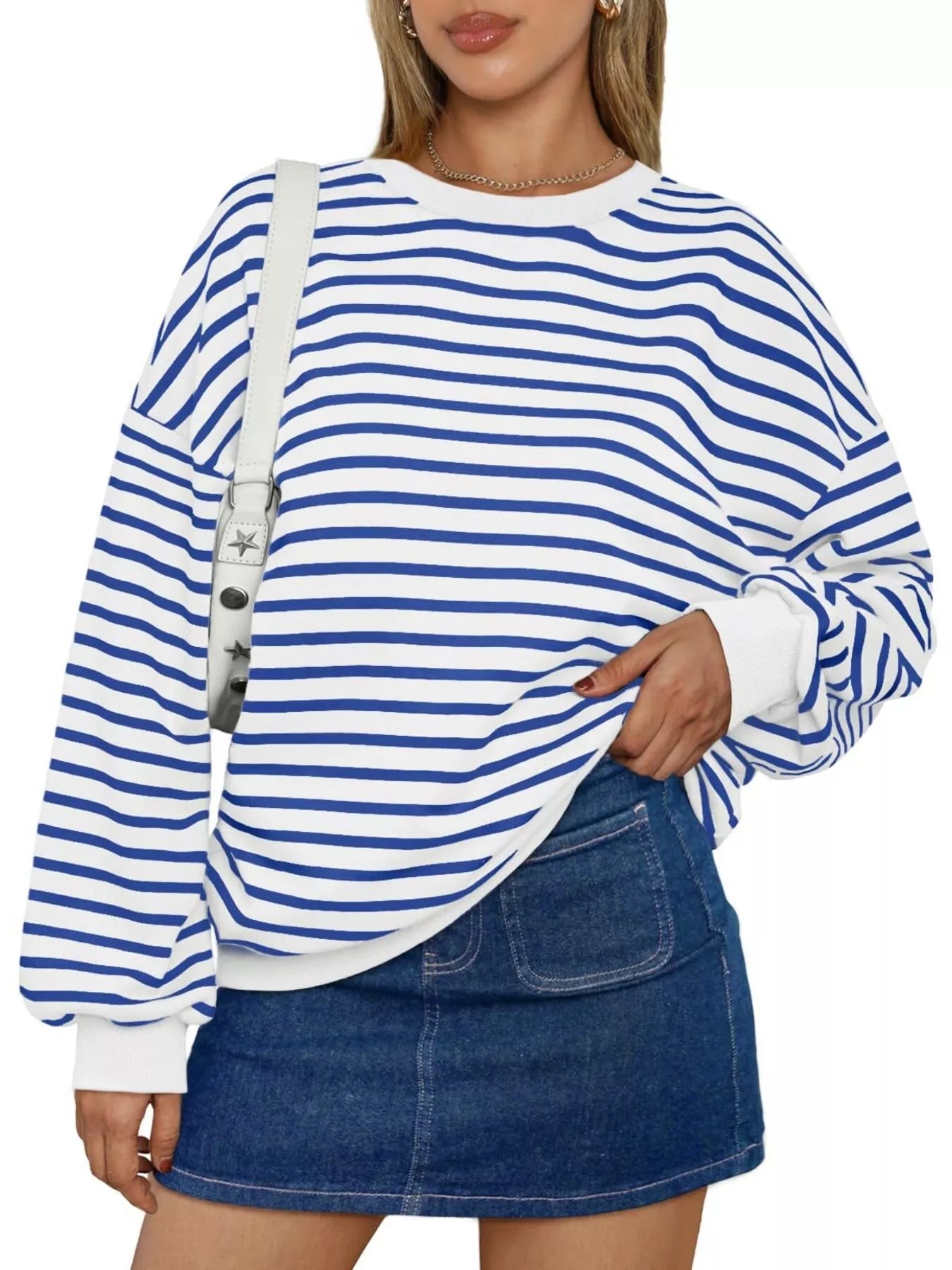Person wearing a blue and white striped sweater with a denim skirt on a white background