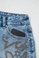 Close-up of blue jeans with decorative stitching on a white background