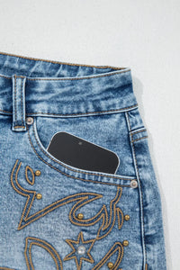 Close-up of blue jeans with decorative stitching on a white background