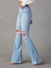Light blue flared jeans with distressing on a gray background