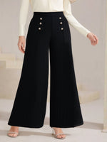 Black wide-leg pants with button details worn by a person on a neutral background