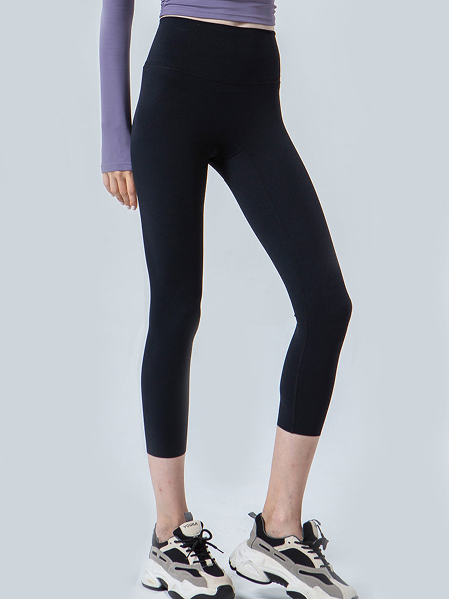 Person wearing black leggings and a purple top on a light gray background