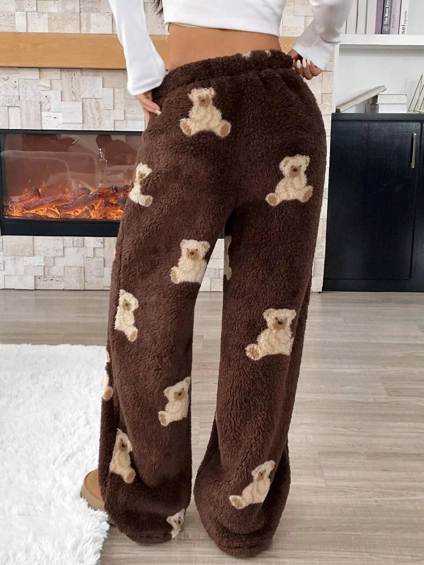 Brown fuzzy pants with teddy bear patterns worn by a person in a home setting.