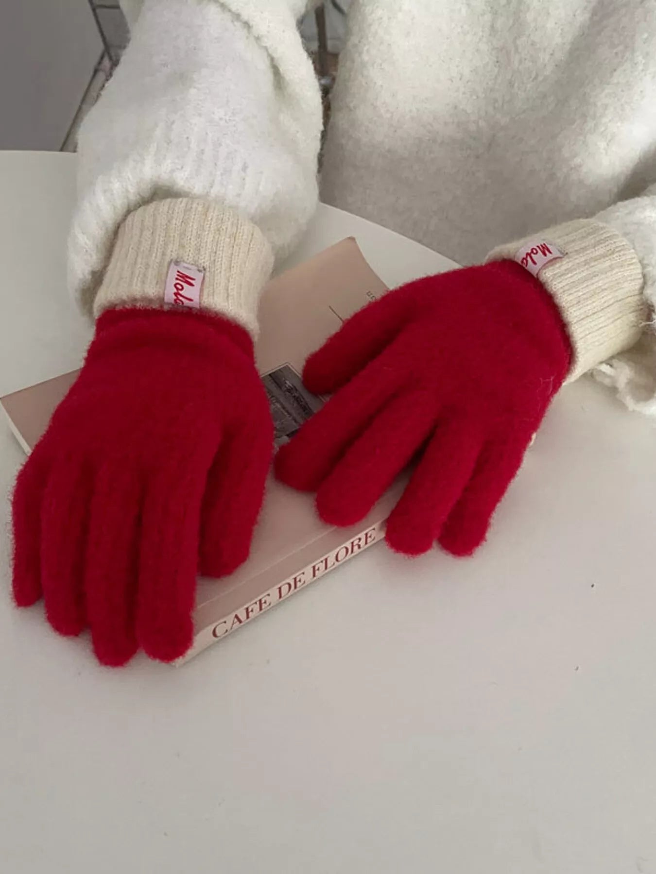 Red gloves with white cuffs on a book