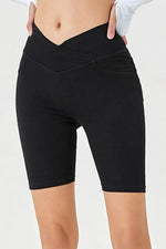 Black high-waisted shorts worn by a person on a white background