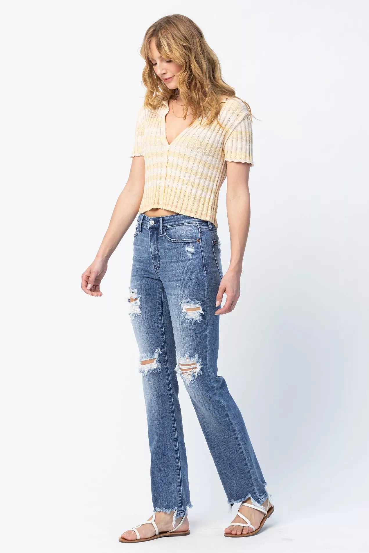 Woman wearing a striped shirt and ripped jeans on a white background