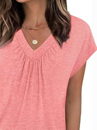 Woman wearing a pink short-sleeve top with a plain background