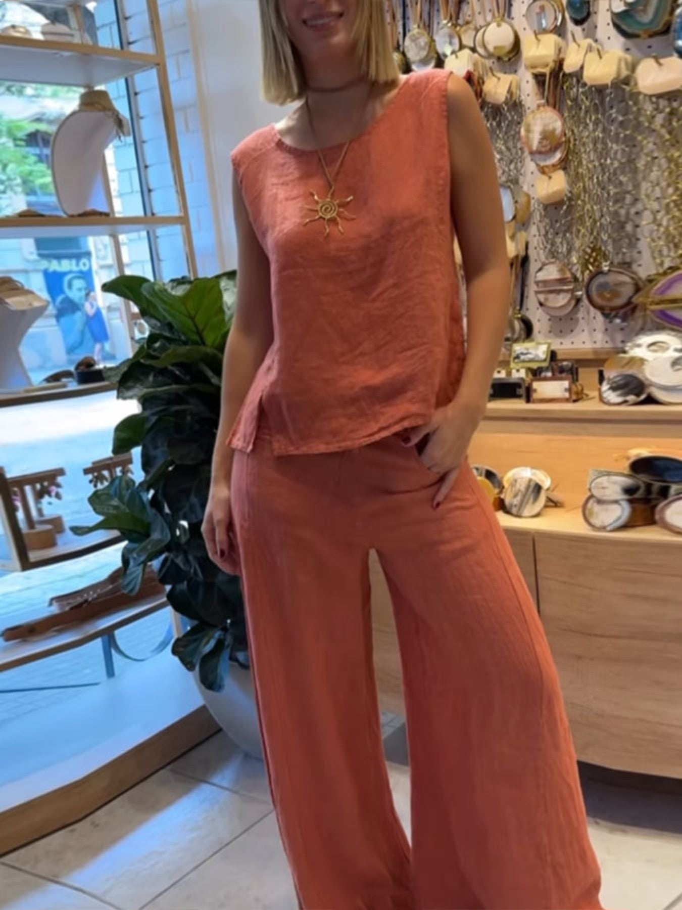 Person wearing a coral sleeveless top and pants in a store setting.