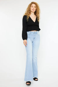 Woman wearing a black top and light blue jeans on a white background