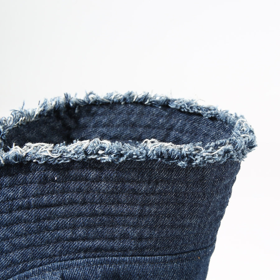 Close-up of a denim bucket hat with frayed edge on a white background
