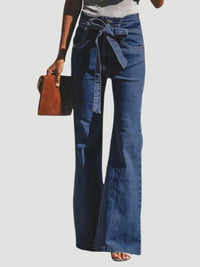 Person wearing blue denim bell-bottom pants with a white background