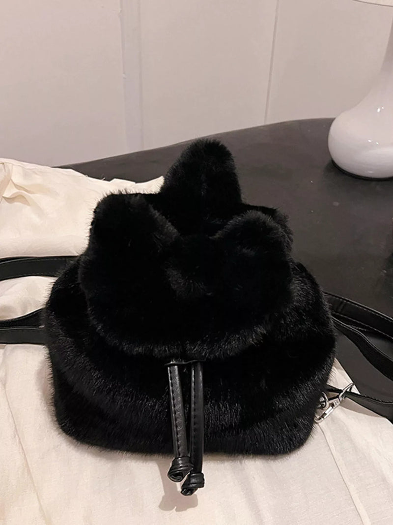Black fur bag on a white surface with a neutral background
