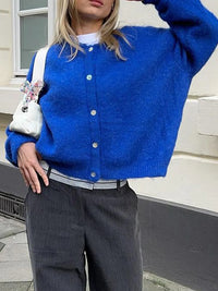 Person wearing a blue cardigan with a white background