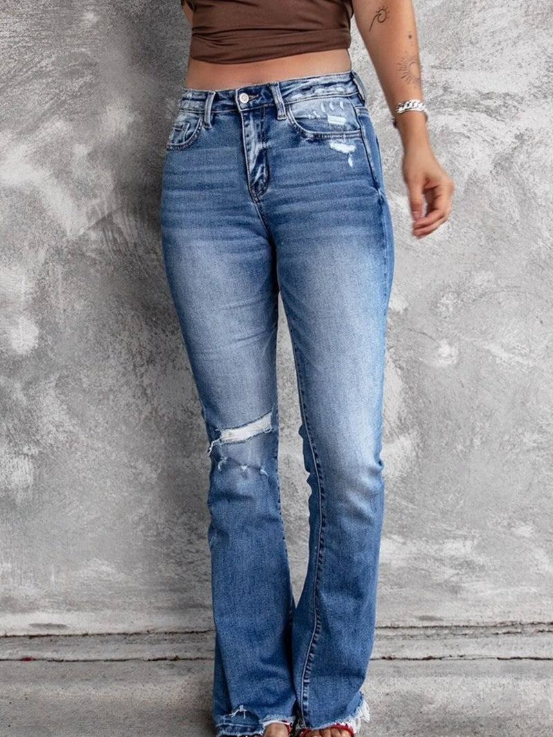 Person wearing blue jeans with a concrete wall background