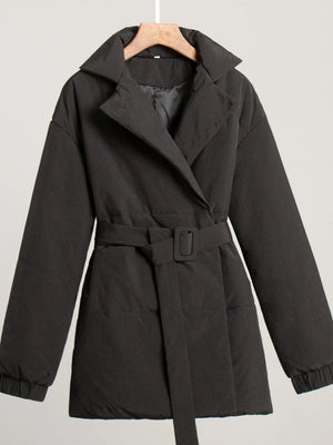 Black coat with a belt on a hanger against a light gray background
