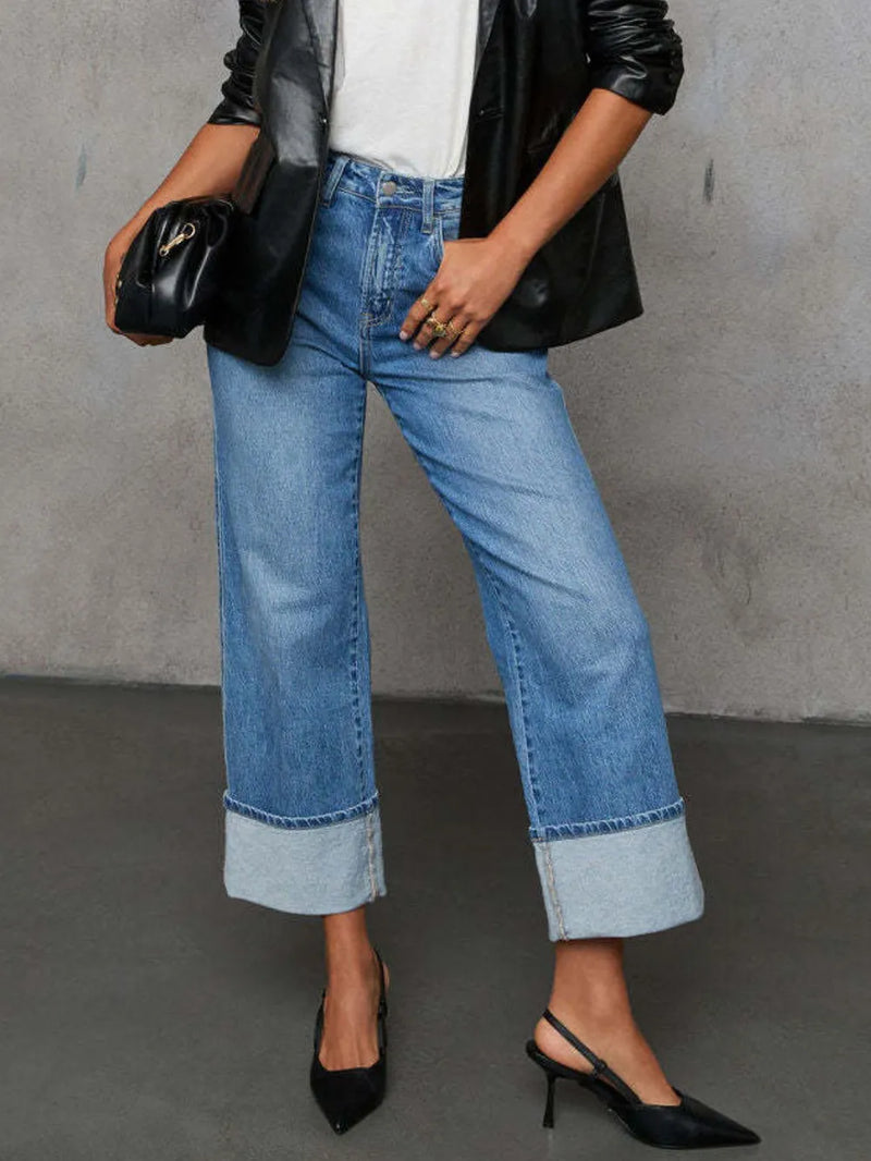 Person wearing blue jeans and black shoes against a gray background