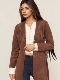 Woman wearing a brown suede jacket with fringe details on a plain background