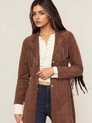 Woman wearing a brown suede jacket with fringe details on a plain background