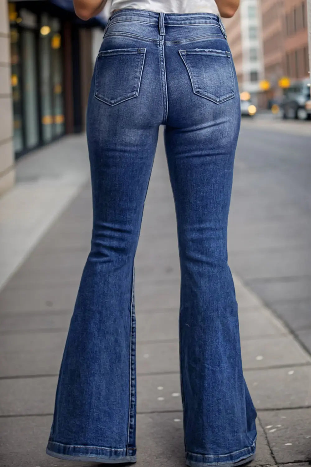 Person wearing blue flared jeans on a city street.