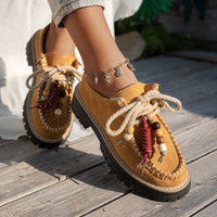 Brown suede shoes with decorative laces on a wooden floor
