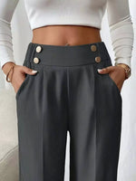 Person wearing dark gray pants with button details and a white cropped top.