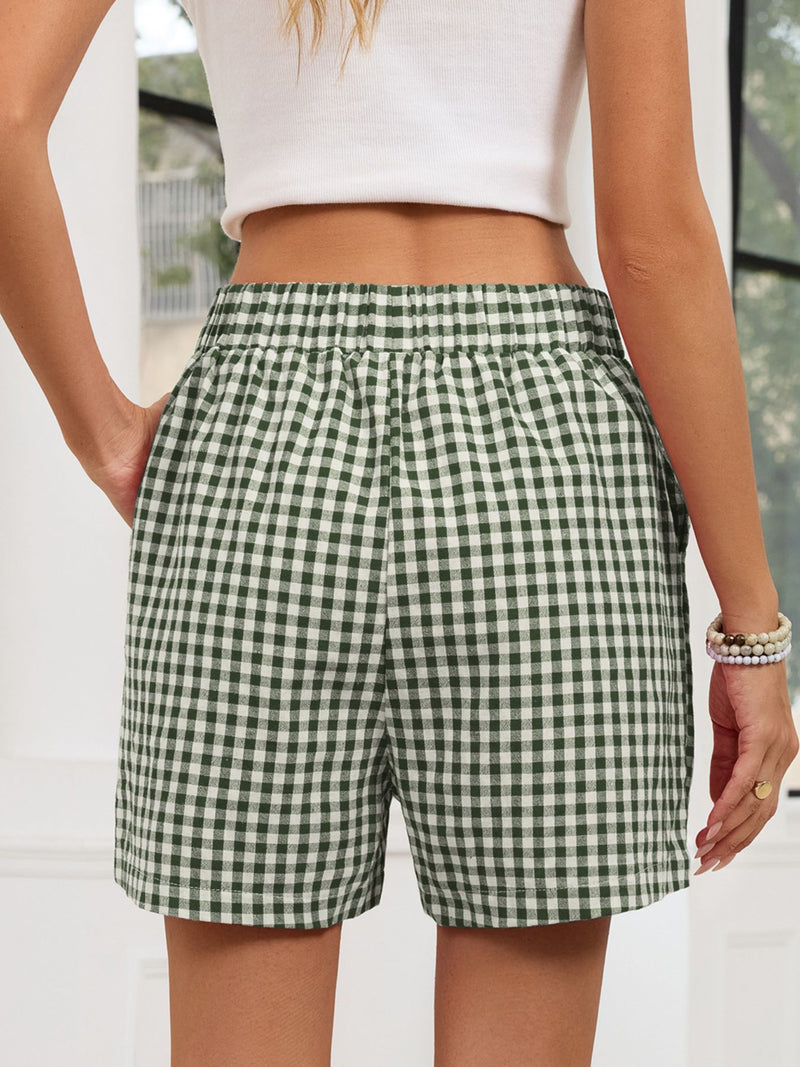 Green and white checkered shorts worn by a person with a blurred background