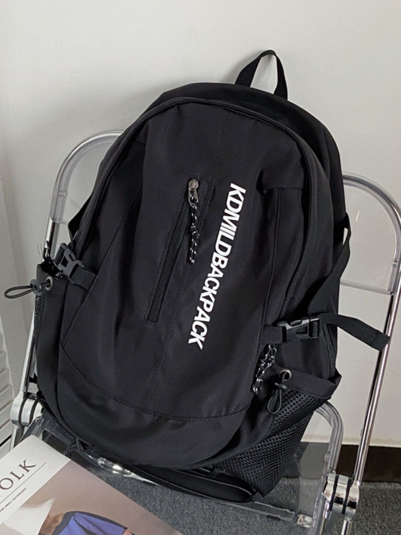 Black backpack with 'KONWILBACKPACK' branding on a clear chair.