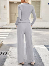 Woman wearing a gray jumpsuit standing on a street.