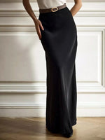 Person wearing a black skirt with a belt against a neutral background