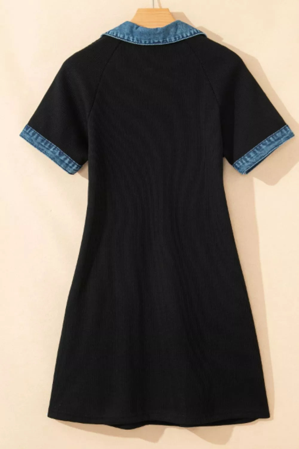 Black dress with blue trim on a beige background