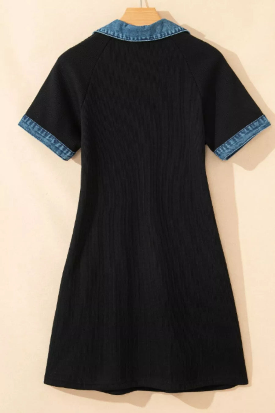 Black dress with blue trim on a beige background