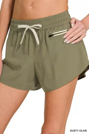 Olive green shorts with a drawstring and zipper pocket on a white background