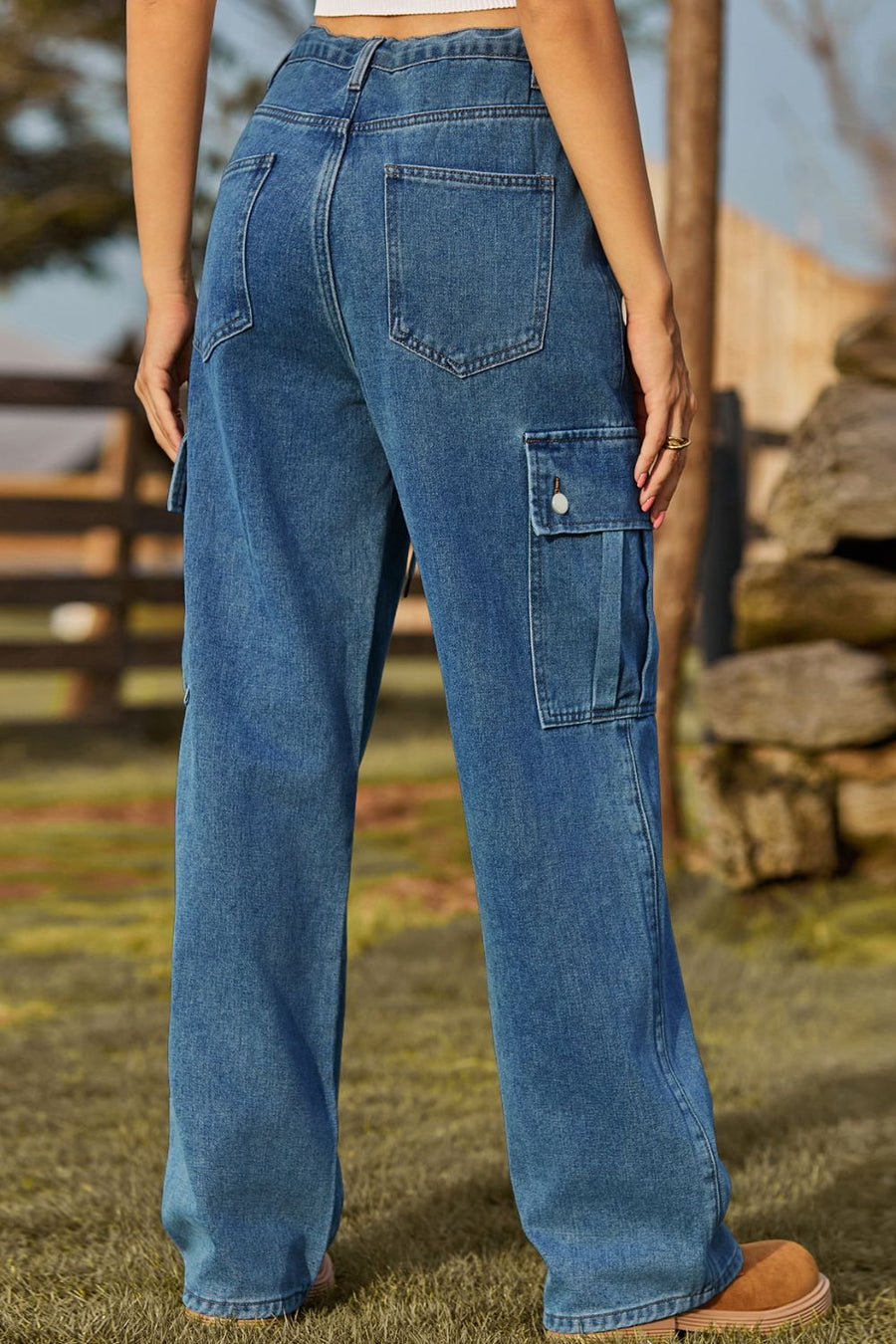 Person wearing blue jeans standing outdoors with a blurred background