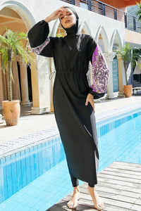 Woman in a black abaya standing by a poolside with a decorative umbrella in the background.