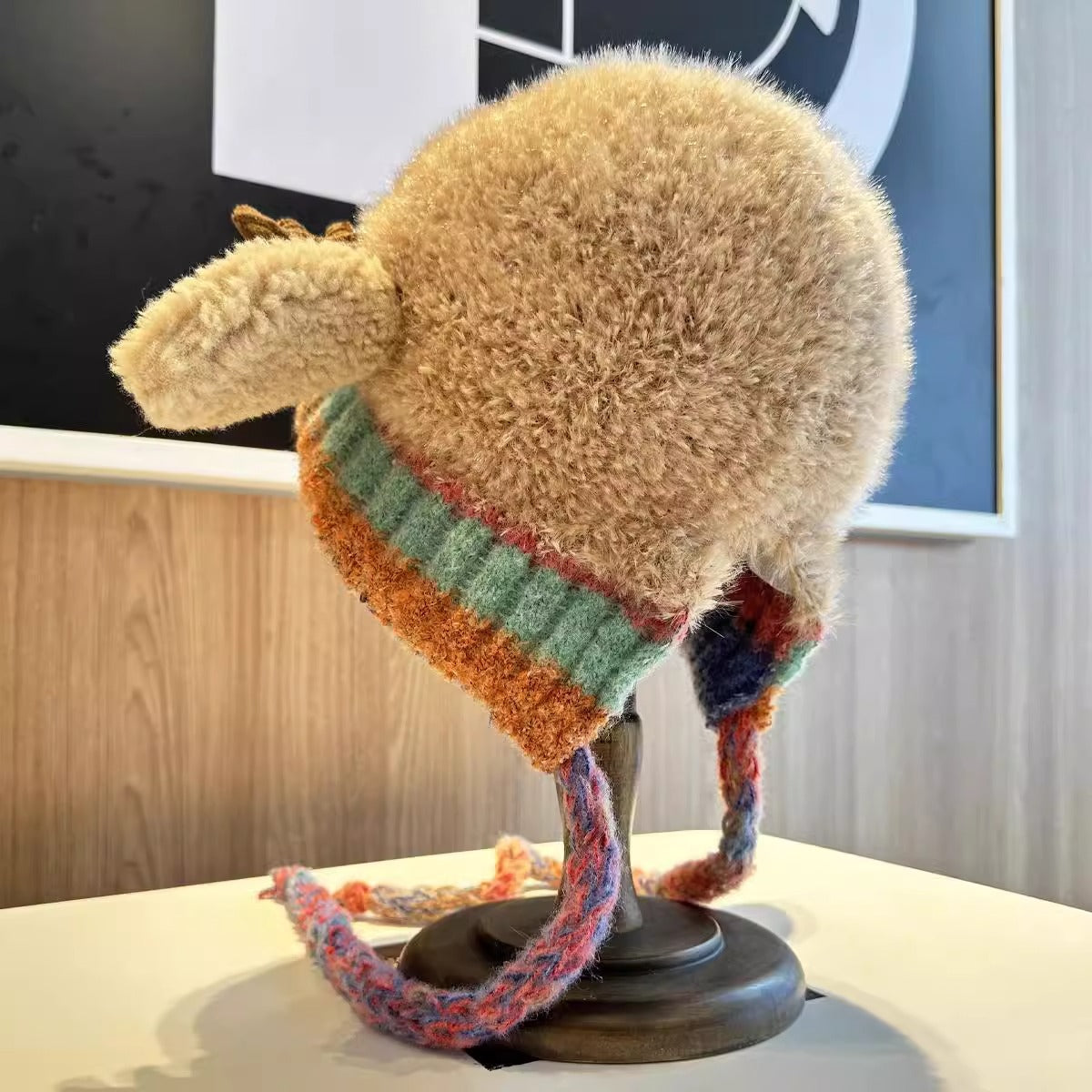 Knitted hat with colorful band on a mannequin head against a blurred indoor background