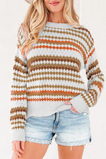 A woman wearing a knit sweater with horizontal stripes in brown, orange, and white, paired with light-wash denim shorts.