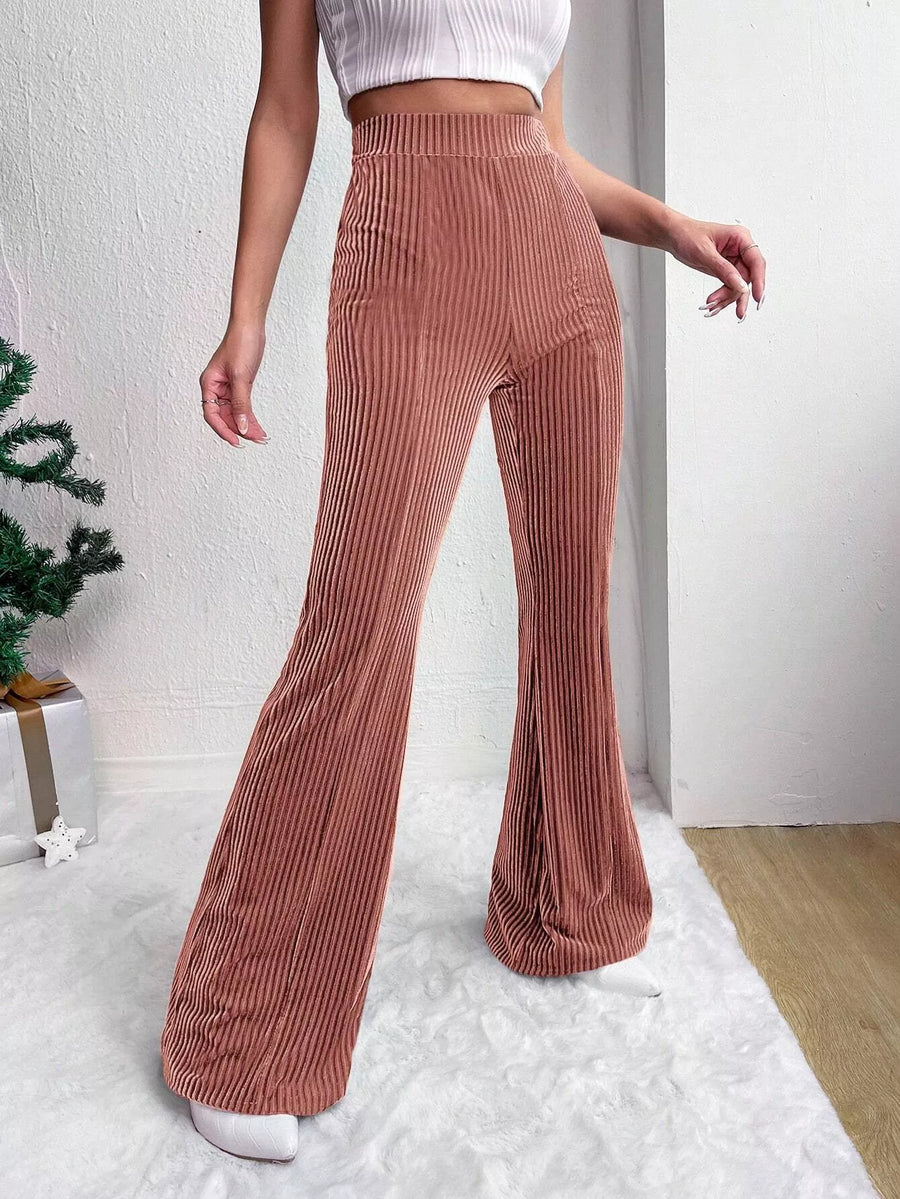 Person wearing brown corduroy pants and a white top indoors.