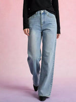Person wearing light blue jeans on a pink background