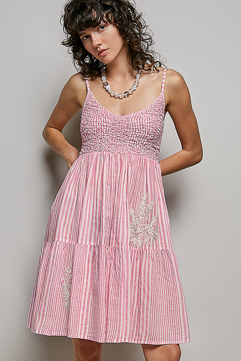 Woman wearing a pink dress with vertical stripes against a gray background