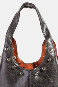 Black leather handbag with studs on a white background