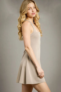 Woman wearing a beige dress against a plain background