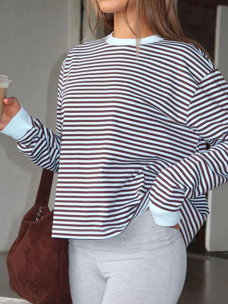 Person wearing a striped shirt and holding a brown bag indoors