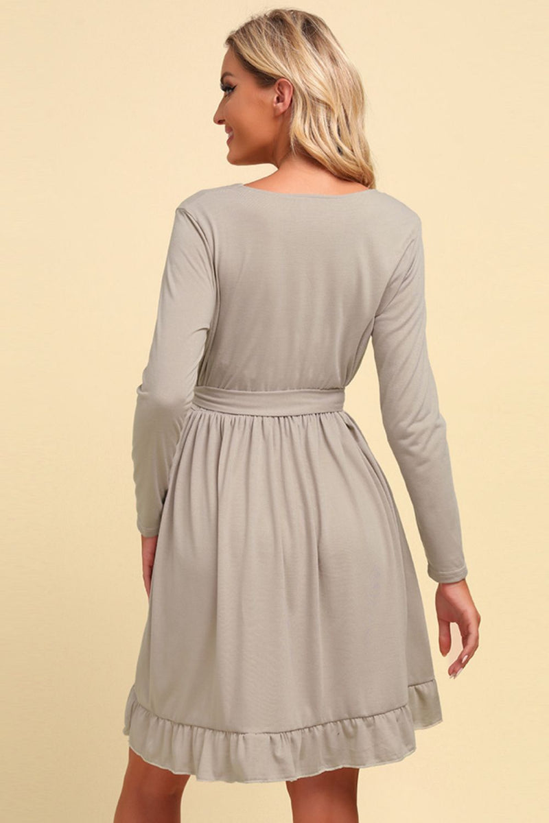 Woman wearing a light gray dress with long sleeves on a beige background