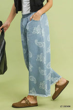 Light denim pants with paisley pattern worn by a person on a green background