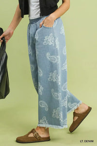 Light denim pants with paisley pattern worn by a person on a green background