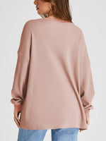 Pink ribbed sweater worn by a person on a white background