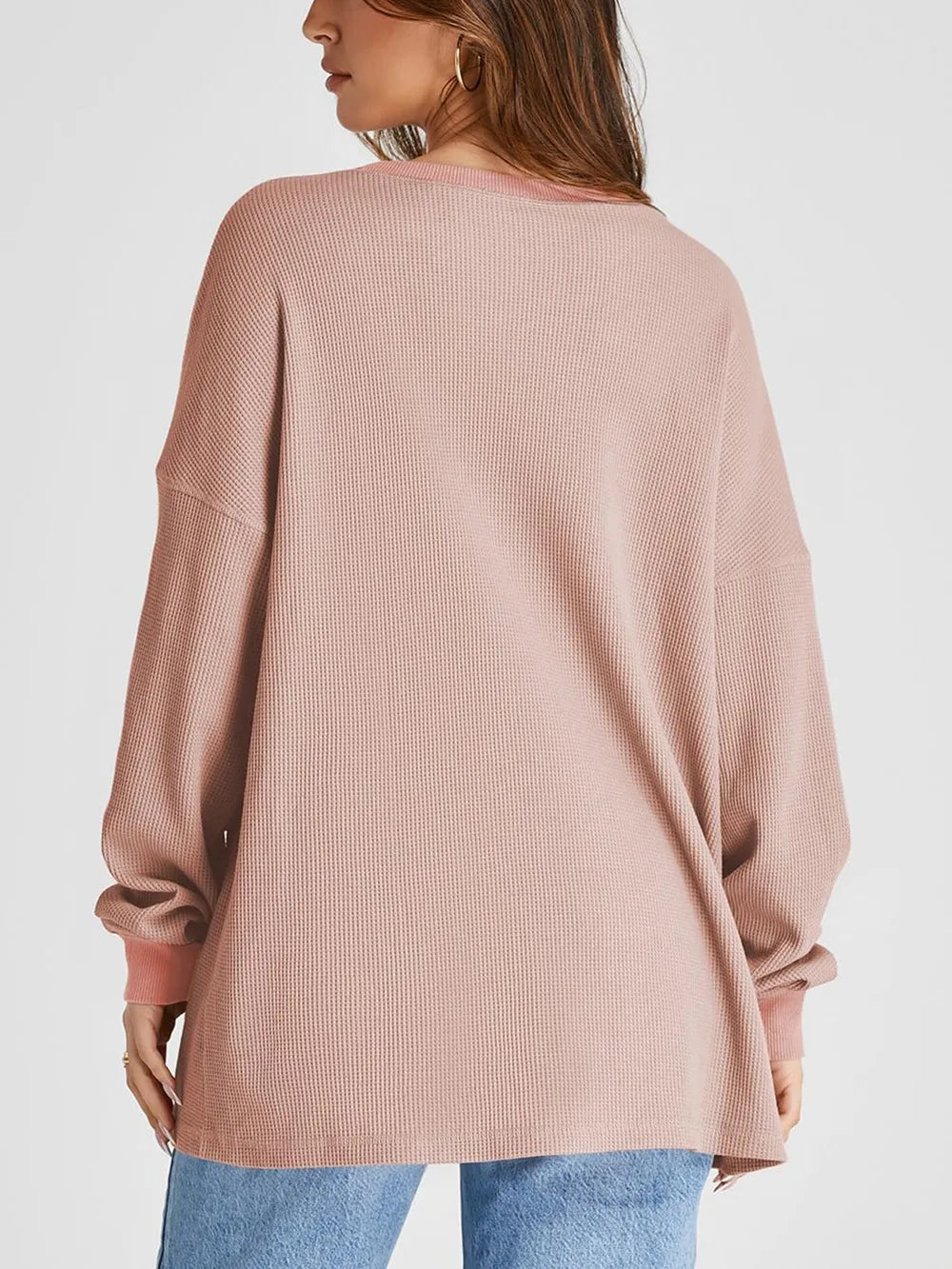 Pink ribbed sweater worn by a person on a white background